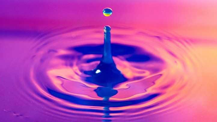 Image of water drop in water with purple light
